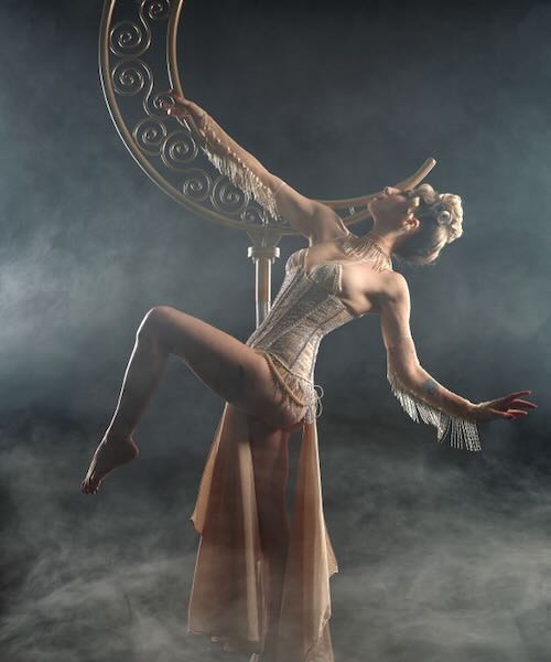Burlesque performer Nita Bon Air dancing on a crescent moon lyra